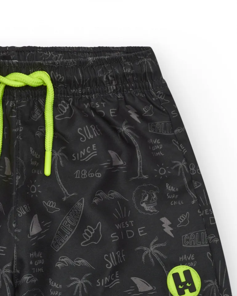 Bañador para niño en negro con estampado surfero y cordón flúor.