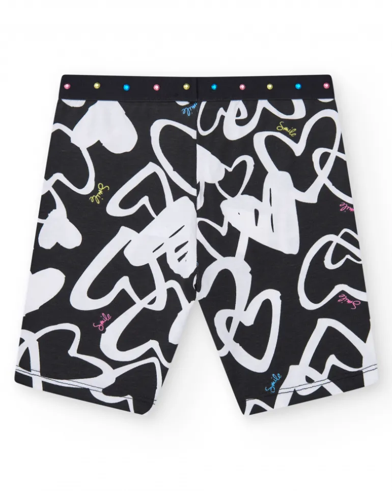 Legging ciclista para niña en negro con corazones estampados y cintura decorada con tachuelas